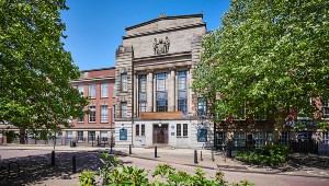 The entrance to the MA Wulfruna building, a set of double doors with plaques, pillar carvings and a stone coat of arms at the top of the building