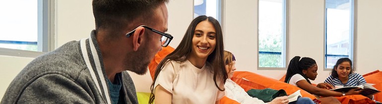 Photograph of students talking to each other while sat in coloured chairs.