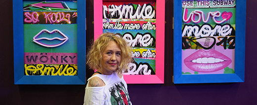 Student standing in front of artwork_ smiling