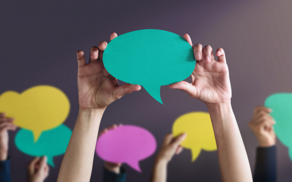 Cut-out multicoloured speech bubbles held in the hands of various people outside the frame.