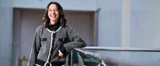 Female student standing at the top of stairs and smiling at camera