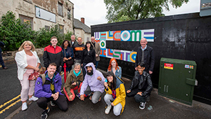 Group of Fine Art students pictured with Pat Mcfaden MP in front of a street sign that says: 