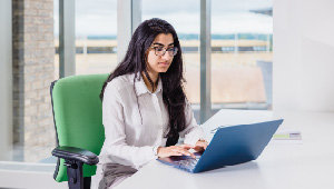 Student sat at desk working on laptop