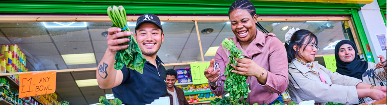 4 students looking at fruit and vegetables outside an afro Caribbean food store.