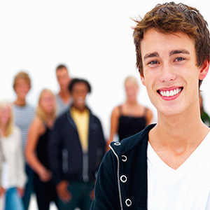 Photograph of a man smiling towards the camera with a small crowd behind him.