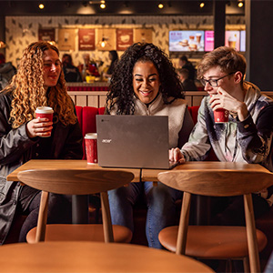 three students looking at a laptop