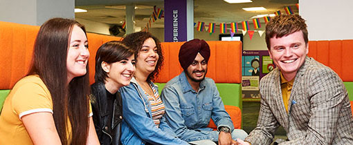 Students sitting around a table talking amongst each other in a communal area.