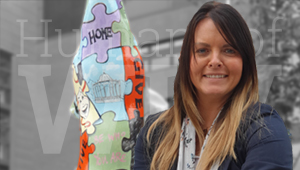 Claire Dickens standing in front of the wolf monument in the City Campus courtyard with a black and white background and text reading Humans of WLV